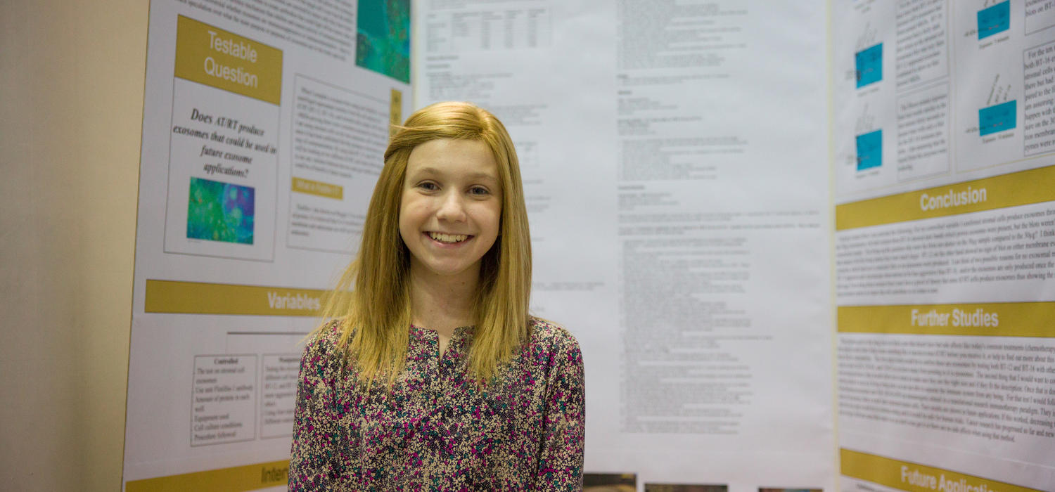 Colette Benko, a Grade 9 student from St. Gregory School, proudly shares her youth science fair project, Investigating Atypical Teratoid/Rhabdoid Tumor Exosomes. Photo by Riley Brandt, University of Calgary 