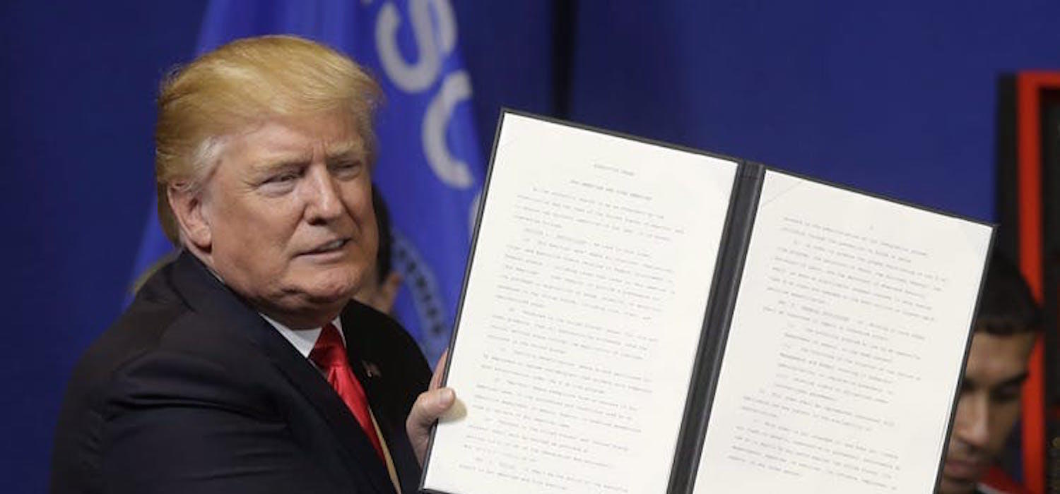 U.S. President Donald Trump holds up an executive order to tighten the rules for technology companies seeking to bring highly skilled foreign workers to the United States in April 2017.
