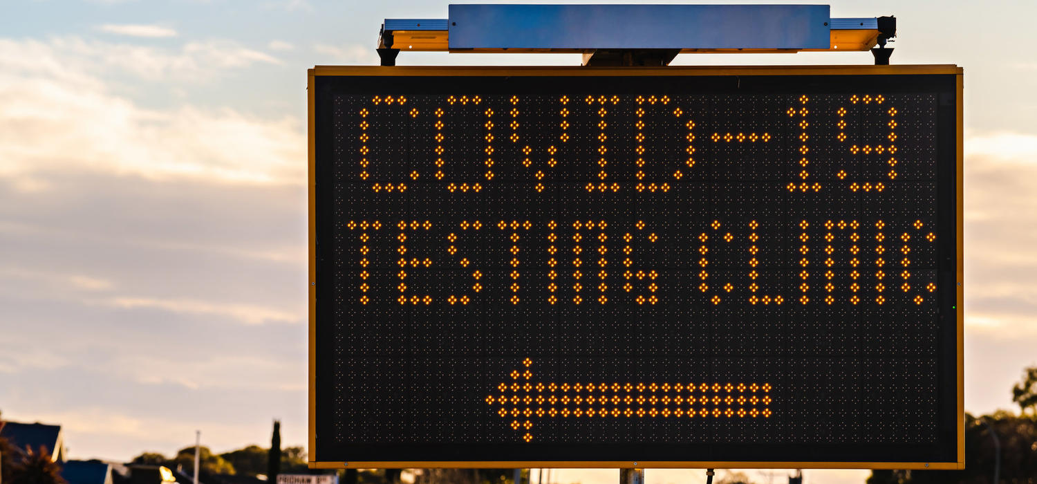 A road sign reads "Covid-19 testing clinic" with an arrow pointing to the left