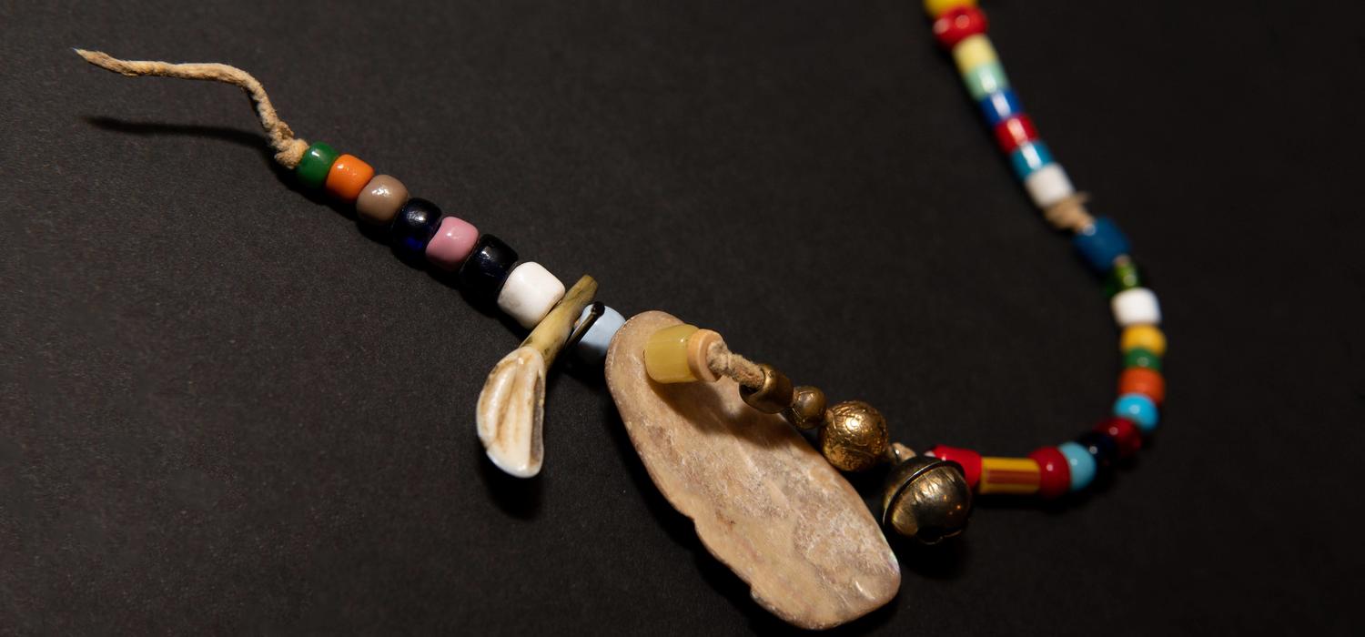 Indigenous trade bead necklace with an elk tooth and a shell. From the Nickle Numismatic Collection.