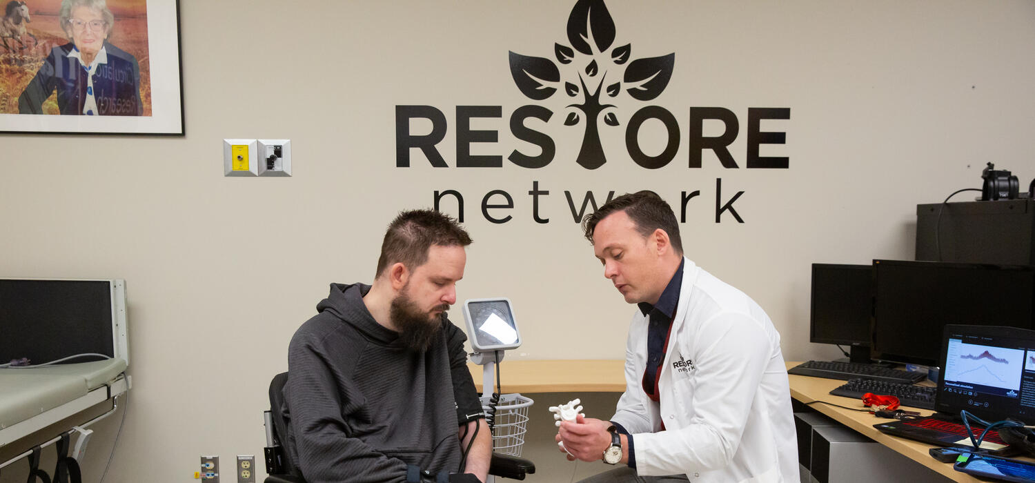 Dr. Aaron Phillips shows Nick Wiltshire the spine stimulation implant that will regulate his blood pressure.