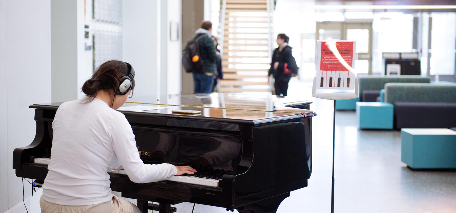 A student plays piano wearing headphones inside the Taylor Institute for Teaching and Learning