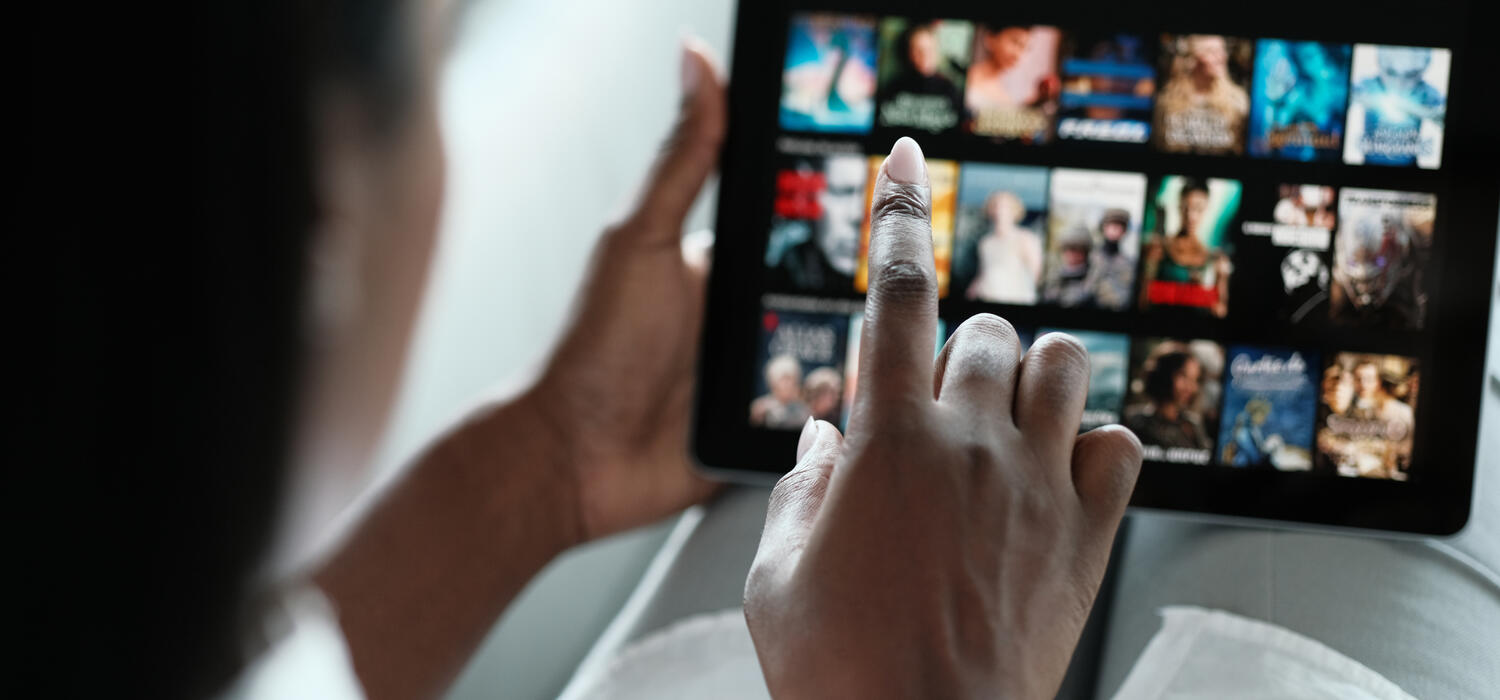A hand scrolls through Netflix on a tablet