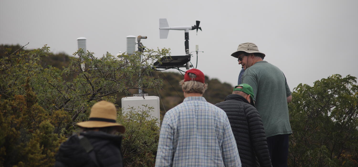 Four men walk up a hill in Maui to assess hydrological equipment