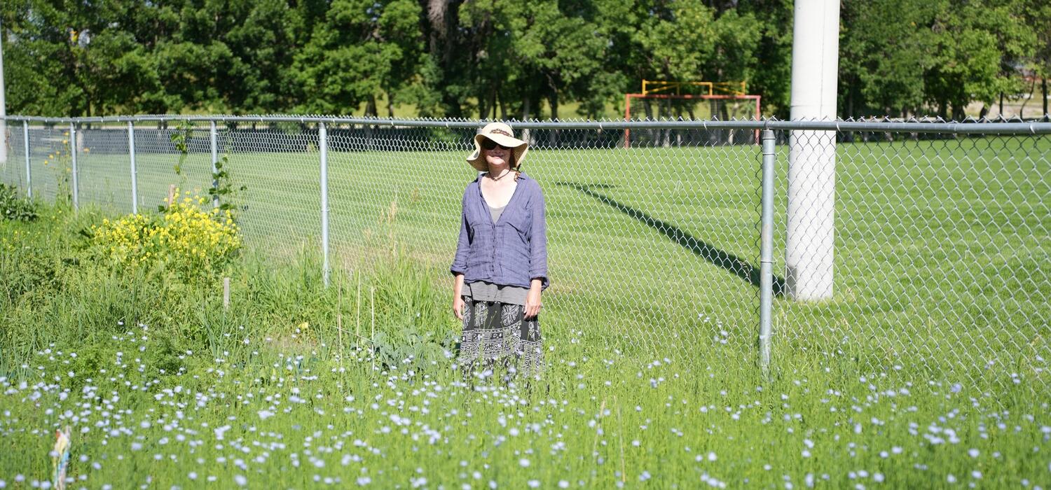 Maria Zytaruk stands beside a field of growing flax plants in the summer of 2023.