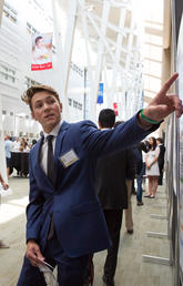 Onlookers intently watch student point at poster