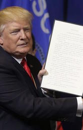 U.S. President Donald Trump holds up an executive order to tighten the rules for technology companies seeking to bring highly skilled foreign workers to the United States in April 2017.
