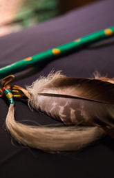 Two feathers lie on a black table top