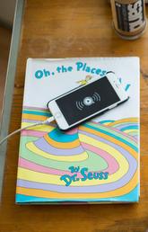 Overhead shot of student wearing maroon hat and looking at Doctor Seuss book