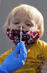 One-year-old Quentin Brown is held by his mother, Heather Brown, as he eyes a swab while being tested for COVID-19 at a new walk-up testing site at Chief Sealth High School in Seattle on Aug. 28, 2020.