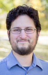 Man with dark hair and beard wearing blue shirt