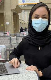 Nabila Bahrami sits at a table with her laptop.