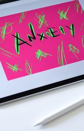 Tablet with "Anxiety" spelled out on the screen on a colourful design