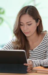 Woman in striped shirt using a tablet device.