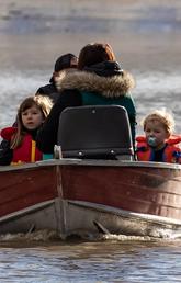 A woman and children who were stranded by high water due to flooding are rescued by a volunteer operating a boat in Abbotsford, B.C., in November 2021.