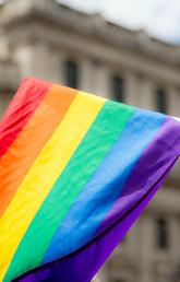 A hand holds a Pride flag