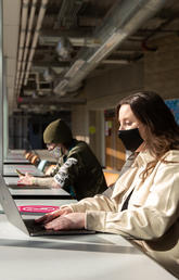 Masked people working at laptops