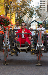 A pilot in a red flight suit drives a mech robot down Calgary's Stephen Ave