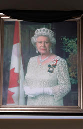 An official portrait of Queen Elizabeth II draped in black hangs in the Atrium at The Military Museums of Calgary