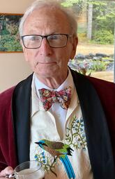 A man wearing a bow tie and holding a cup of tea