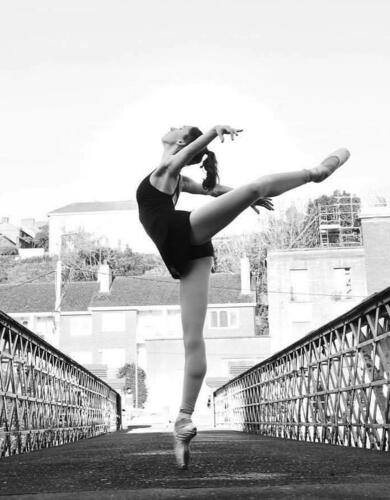 A woman dances on a bridge