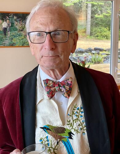 A man wearing a bowtie and holding a cup of tea