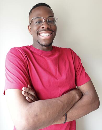 A man wearing glasses and a red shirt smiles at the camera