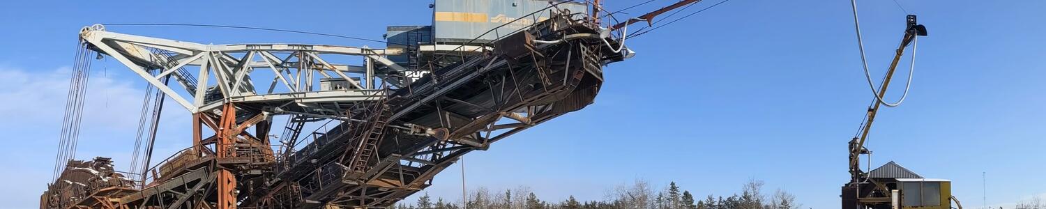 large bucketwheel excavator on snowy ground with blue skies in the background