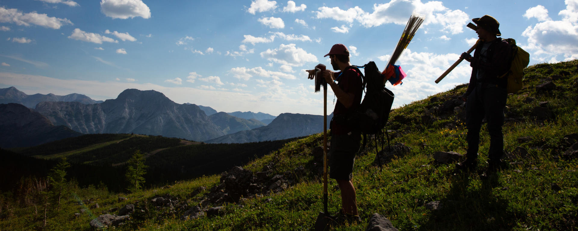 A silhouette of two researchers in the Rocky Mountains