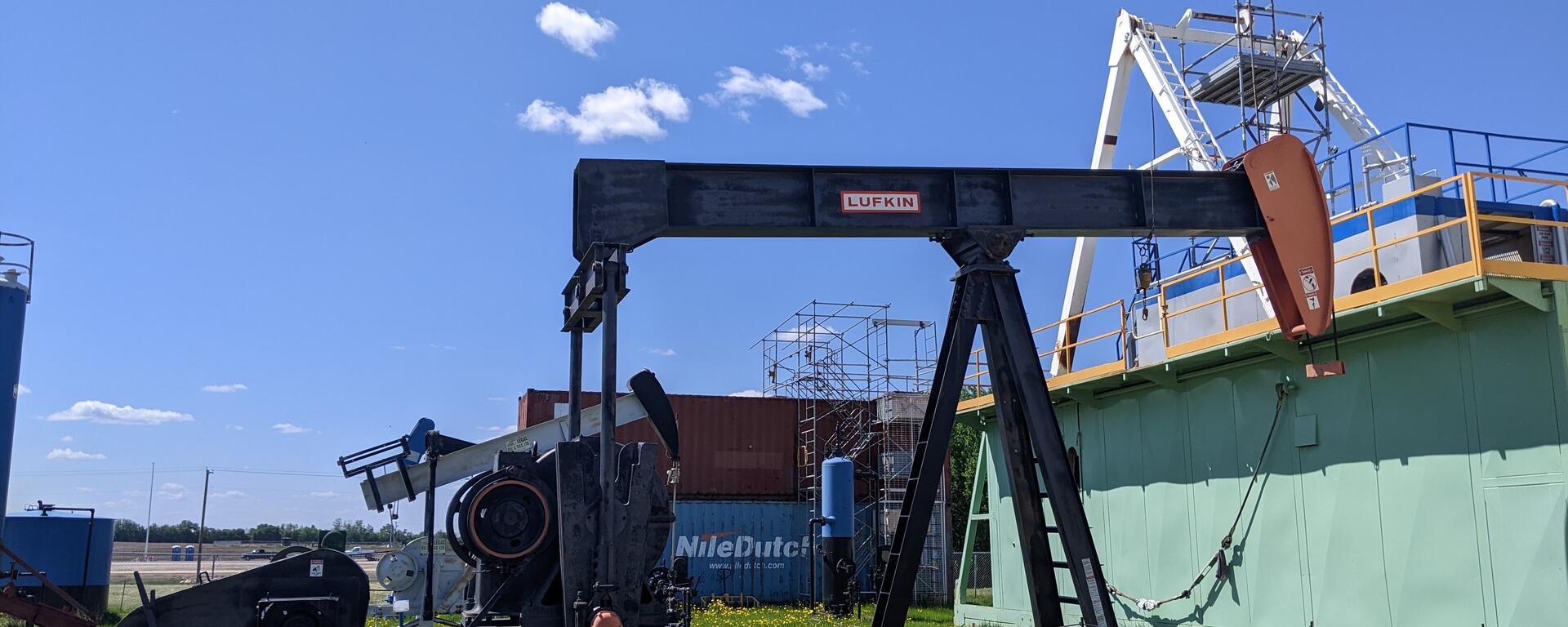 pump jack on grass in front of blue skies