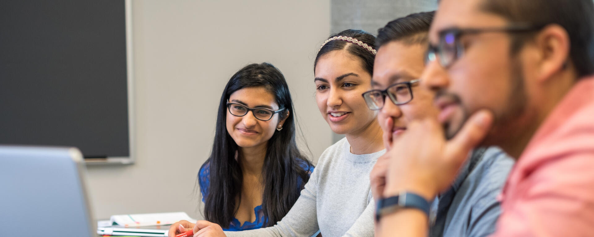 Four students watching something on a laptop