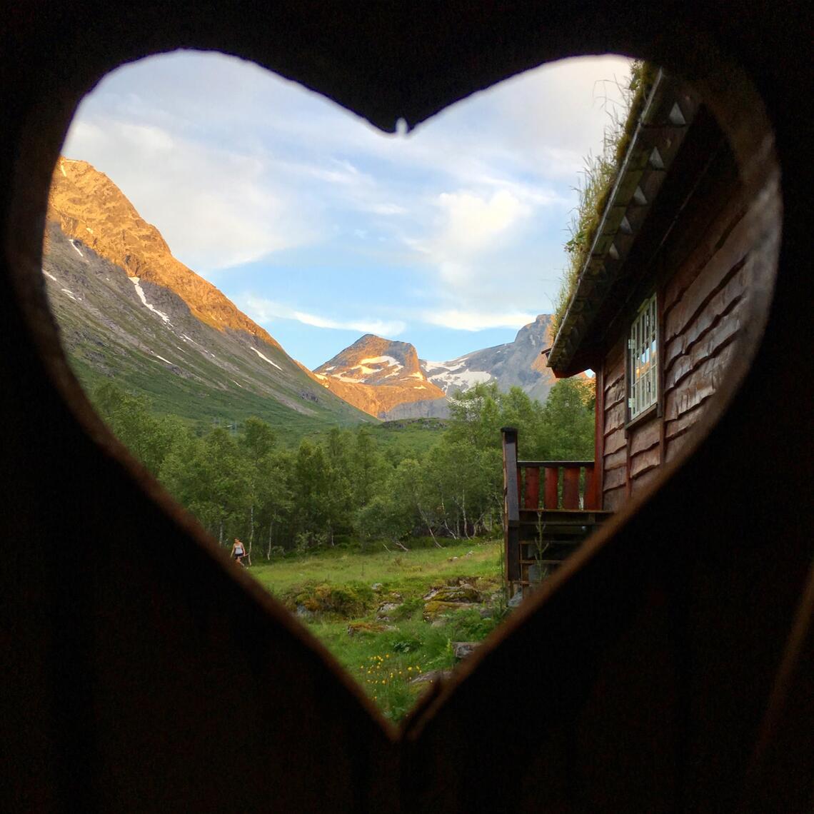 Photo of a mountain framed by a heart from the inside of a building window.