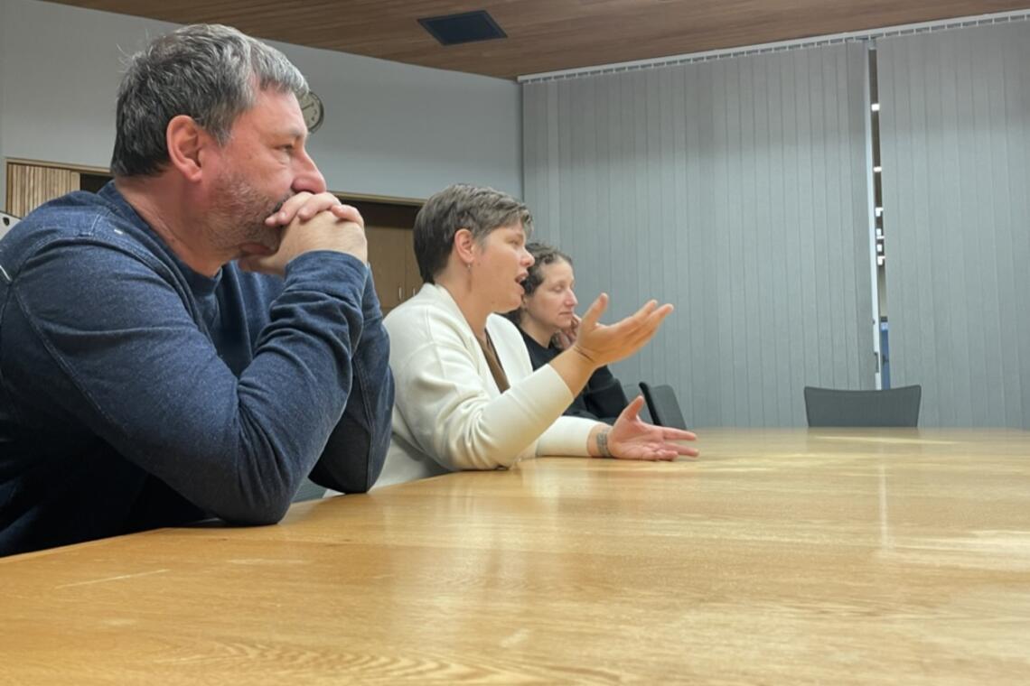 three people sitting around a conference table talking