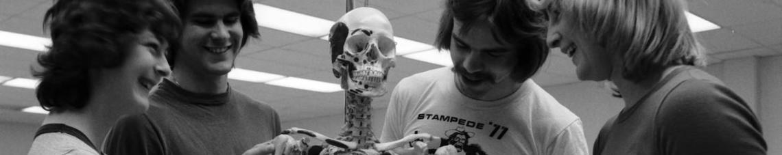 Four University of Calgary students studying a human skeleton in a Physical Education lab