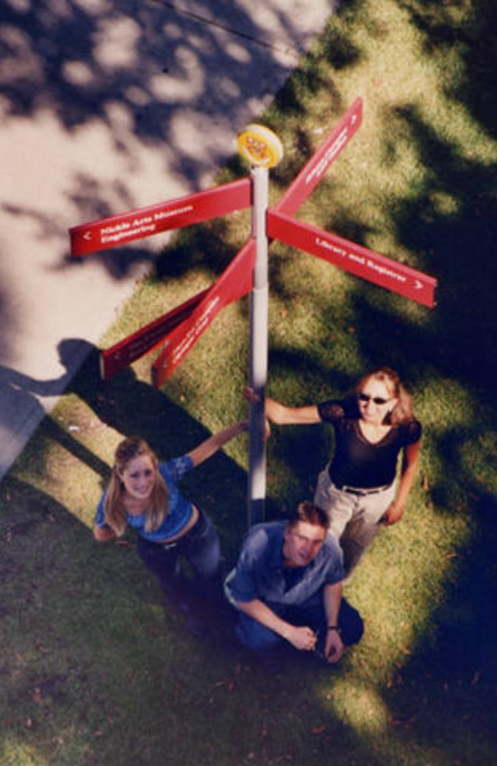 Students outdoors near a campus sign post, 2000. Students outdoors near a campus sign post, 2000.