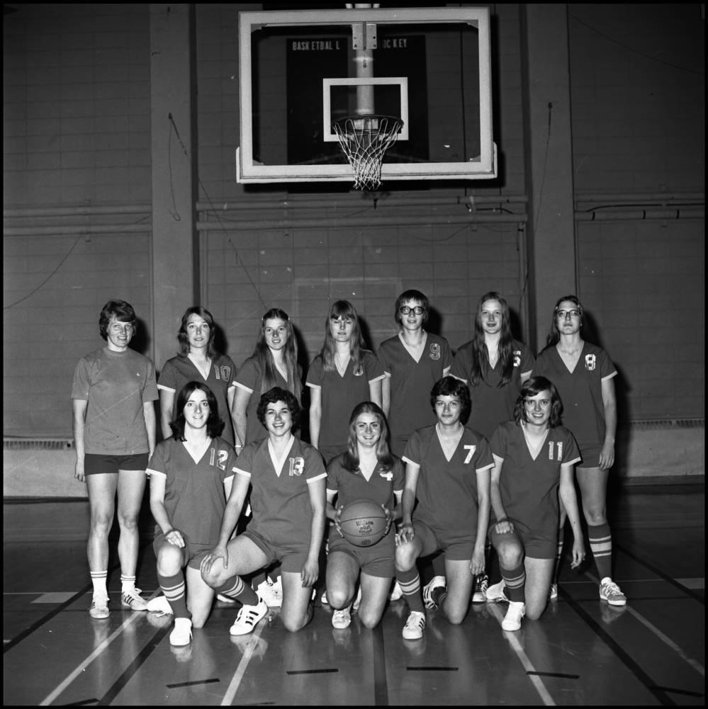 The University of Calgary Dinosaurs women's basketball team posing as a group in front of a basketball hoop. The University of Calgary Dinosaurs women's basketball team posing as a group in front of a basketball hoop.