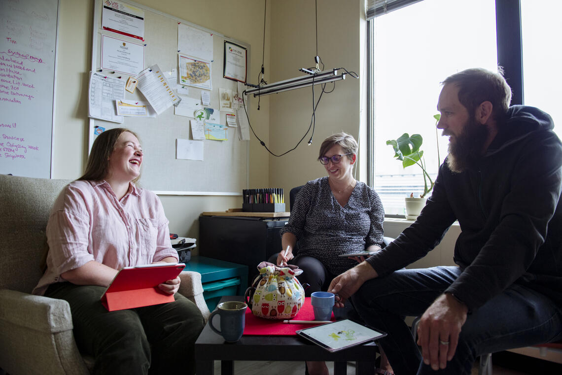 A student laughs with her supervisors in an office.