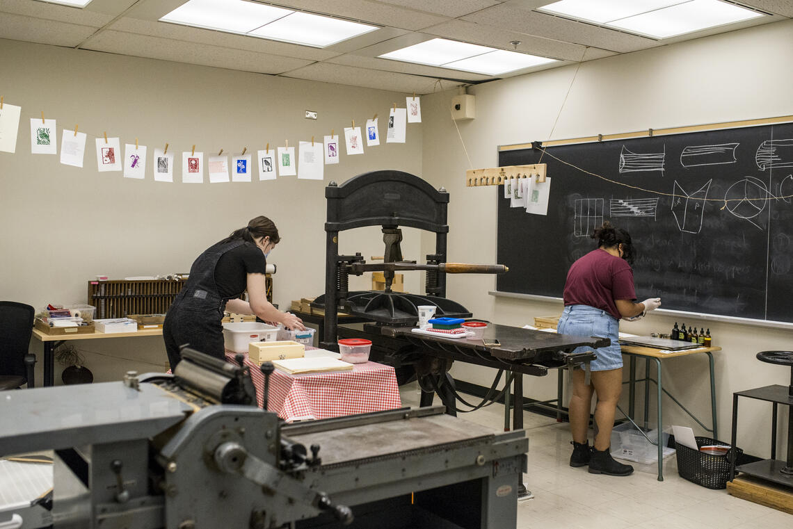 Two student working in the Book Arts lab making paper and printing paper.