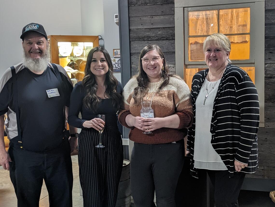 four people in front of an exhibit at the Canadian Energy Museum, posing and smiling