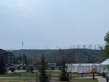 tents in foreground and burned hillside in background with smoky skies