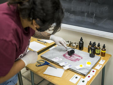 A student rolls handmade ink on a slab.
