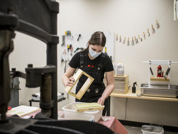 A student uses a frame to make paper out of compost kitchen scraps.