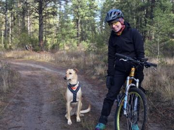 A dog with a woman on a bike.