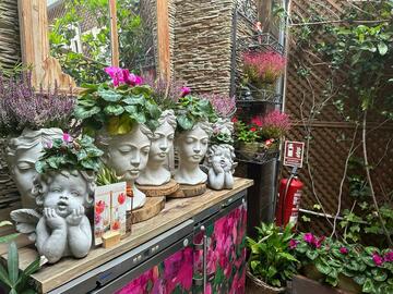 A bench with small statues and pink leafy flowers