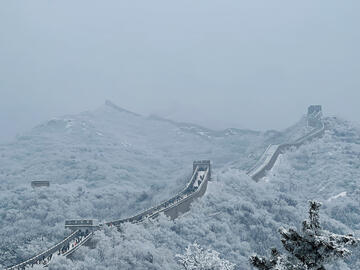 Looking down over the Great Wall as it fades into the distance on a snowy foggy day