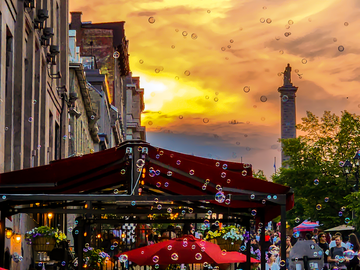 A street corner and outdoor patio at sunset with bubbles in the sky