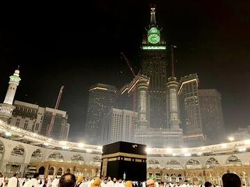 Observing pilgrims moving around the Kabbah shrine at night, with a tower overhead