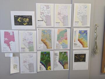 series of wildfire maps pinned on a wall