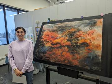 young woman standing in front of her artistic work