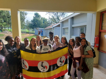 UCalgary and MUST students pose outside holding the Ghanaian flag